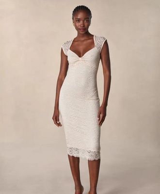 une femme en robe blanche prend la pose pour une photo