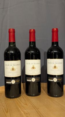 three bottles of wine sit on a wooden table in front of a gray wall