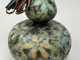a green and black vase with a cord on top of it