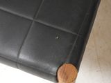 a black leather bench with wooden legs and a wooden seat