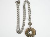silver chain with a donut pendant attached to it on a white surface