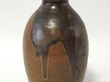 un vase marron posé sur une surface blanche, avec un fond blanc