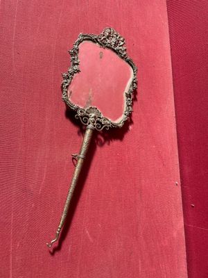 un vieux miroir d'où sort un bâton, posé sur un tissu rouge