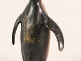 a small black penguin that is standing on a white surface