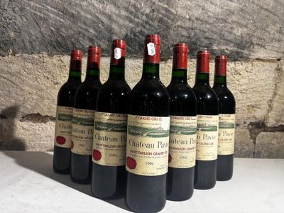 six bouteilles de vin rouge alignées sur une table devant un mur de pierre