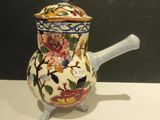a small ceramic teapot with a handle on a table