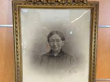 an old picture of a woman in a black dress in a gold frame