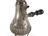 une cafetière ancienne en argent avec une poignée en bois sur fond blanc