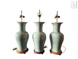trois vases verts posés sur un support en bois