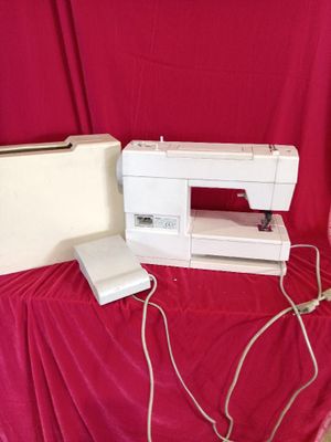 une machine à coudre blanche posée sur un tissu rouge