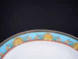 a blue and orange plate with gold trim on a black background