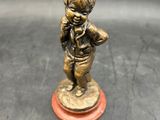 bronze figurine of a little boy with a hat and tie on a red base