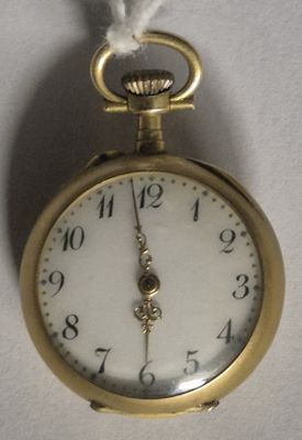 une montre à gousset en or suspendue à un mur blanc