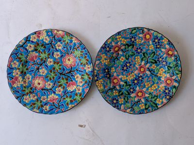 two plates with flowers on them sitting on a white surface