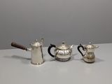 deux théières en argent et une cafetière posées sur une table