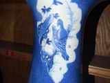 a blue vase with a bird on it sitting on a shelf