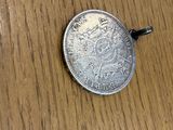 a silver coin on a wooden table with a black cord