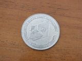 a silver coin on a wooden table with a picture of a man on it