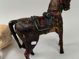 statue of a horse with a saddle next to a rock