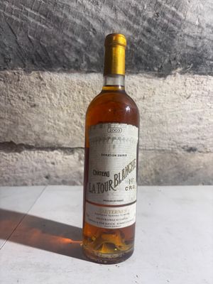 a bottle of liquor sitting on a table next to a stone wall