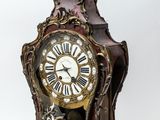 a clock that is sitting on a stand on a white surface