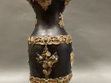 a black and gold vase sitting on a stand