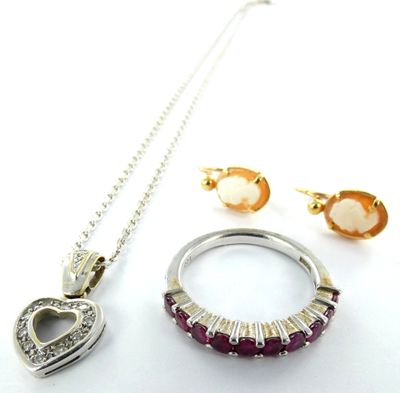 un collier, des boucles d'oreilles et une bague posés sur une surface blanche