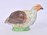 un oiseau en céramique posé sur un socle vert