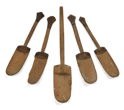 quatre vieilles pelles en bois sont alignées sur une surface blanche