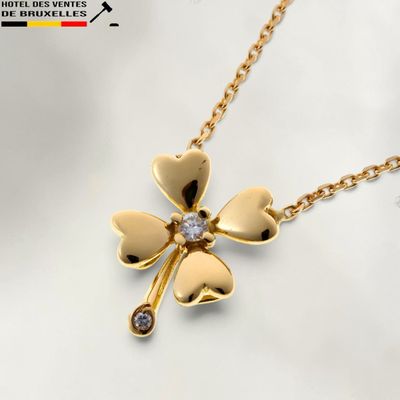 un gros plan sur un collier en or orné d'un pendentif en forme de trèfle à quatre feuilles