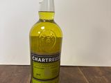 une photo d'une bouteille de Chartreuse posée sur une table en bois