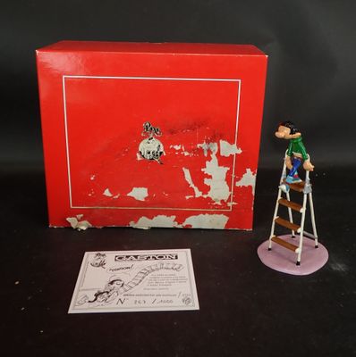 une petite figurine représentant un homme sur une échelle, à côté d'une boîte rouge
