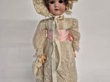 an old fashioned doll with a bonnet and dress on a white surface