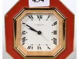 a small red clock with roman numerals on it