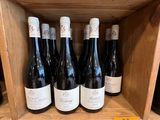 Plusieurs bouteilles de vin sont posées sur une étagère en bois dans un caviste.