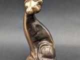 statue of a cat sitting on its hind legs on a gray surface
