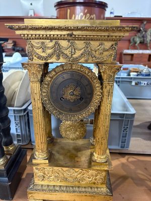 a gold clock sitting on top of a wooden table