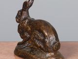 a bronze statue of a rabbit sitting on a table