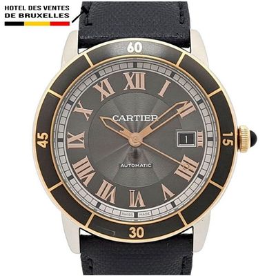 La montre est noire et dorée, avec des chiffres romains sur le cadran.