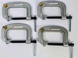 quatre colliers métalliques fixés sur une surface blanche à l'aide de vis et d'écrous