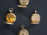 four different types of pocket watches are displayed on a black surface