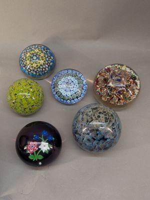 six different colored glass balls sitting on a white surface