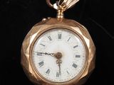 a gold pocket watch with roman numerals on the face