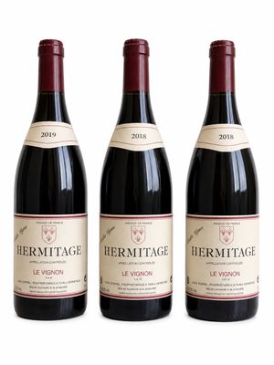 trois bouteilles de vin rouge posées l'une à côté de l'autre sur une surface blanche