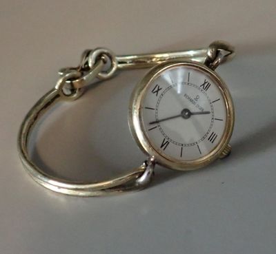 une montre en argent, attachée à une chaîne, posée sur une table