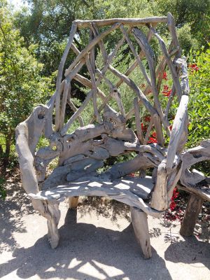 a wooden bench made out of branches in the middle of a garden