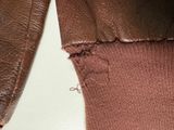 a close up of a brown leather jacket with a hole in it