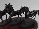 three statues of horses running on a wooden base