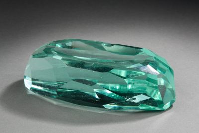 une pierre de couleur émeraude posée sur une surface grise