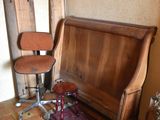 a wooden bench in the corner of a room with a chair